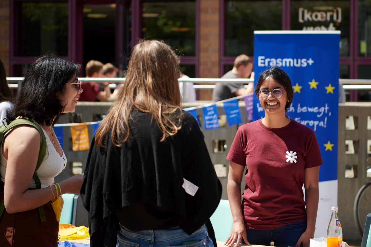 Zwei Studierende stehen an einem Erasmus-Stand und lassen sich beraten. 
