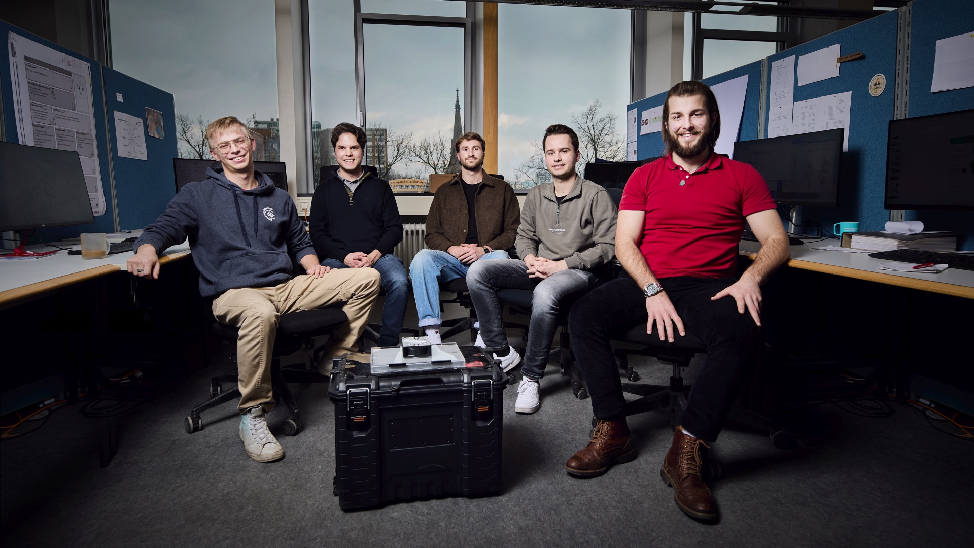 Die fünf Mitglieder des Teams "Evercell" sitzen in einem Büro um das von ihnen entwickelte Produkt herum.