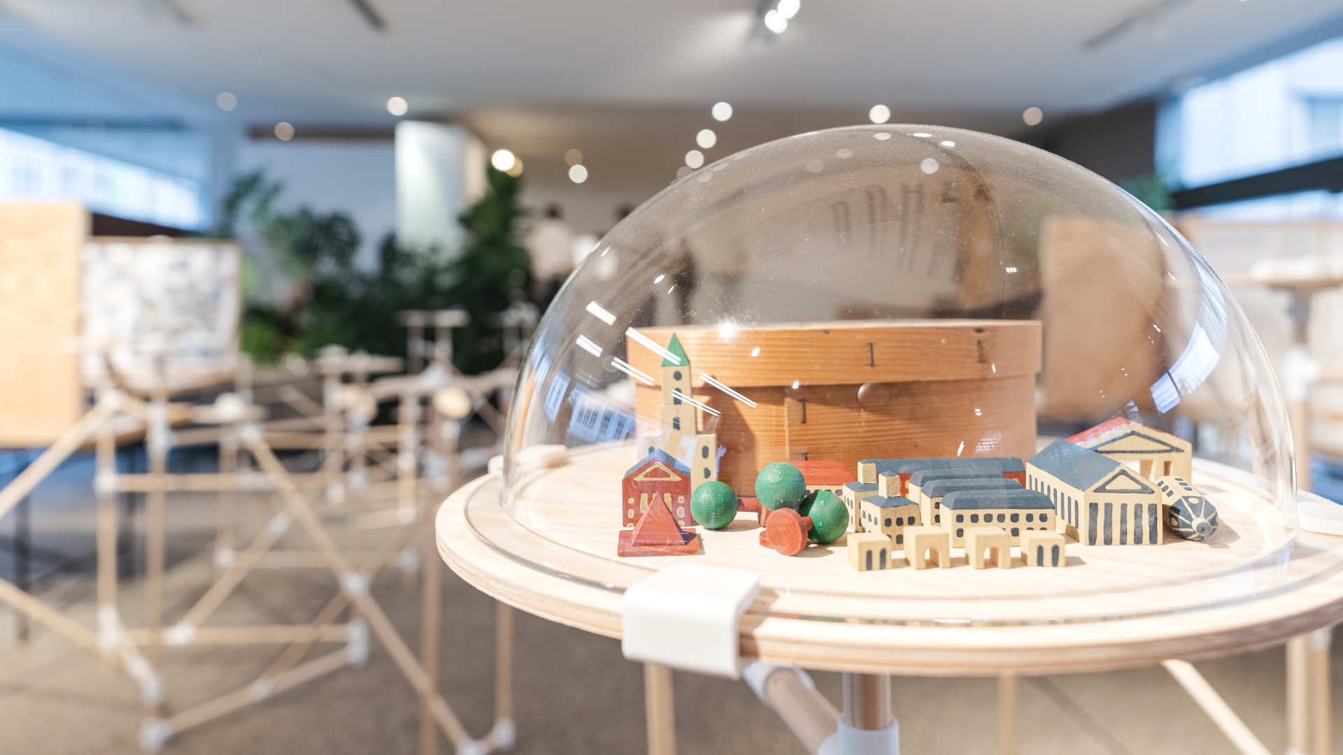 Miniatur-Stadtmodell aus Holz unter Schutzhaube in einem modernen Ausstellungsraum.