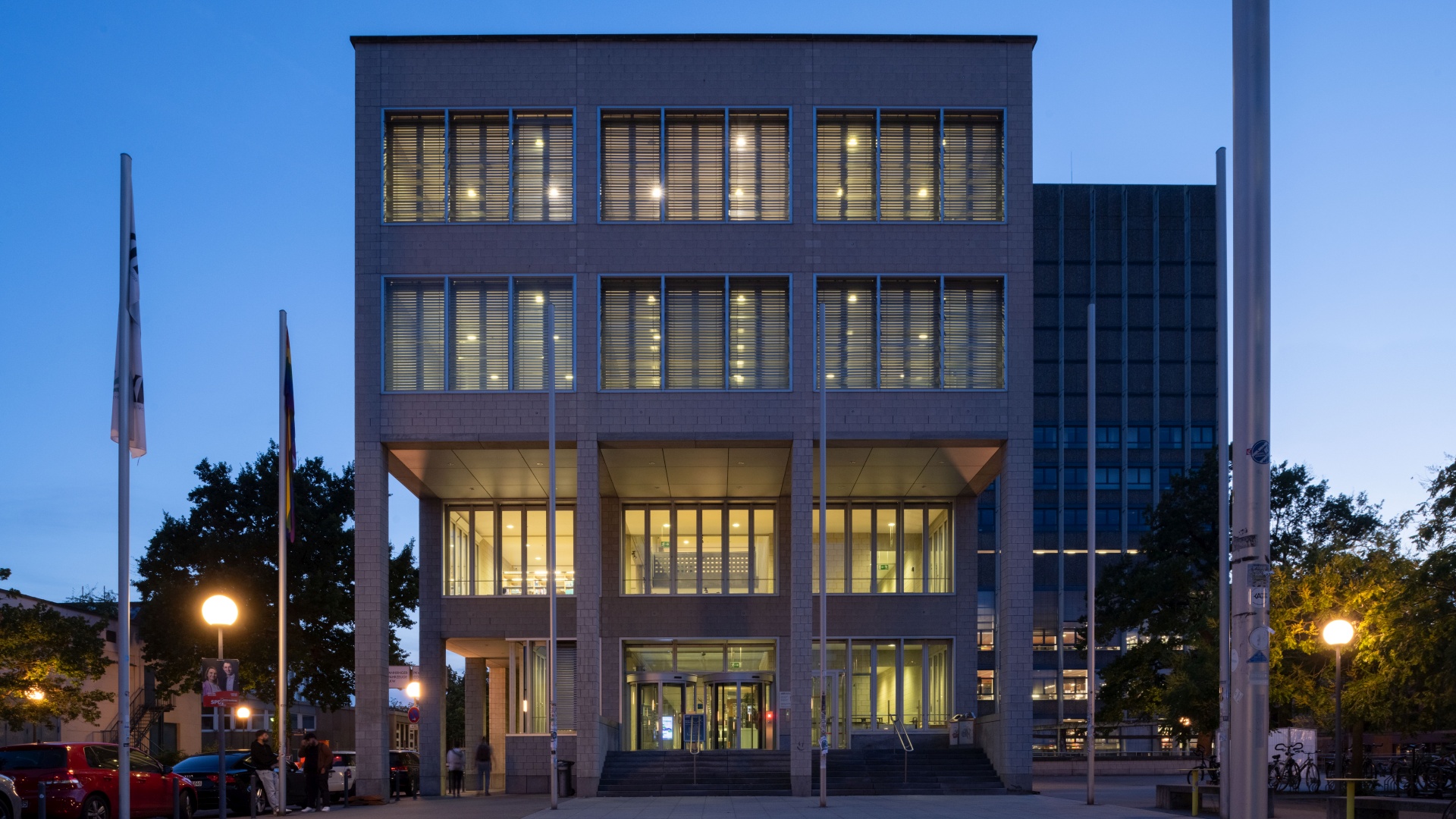 Modern university building facade with illuminated windows at dusk.