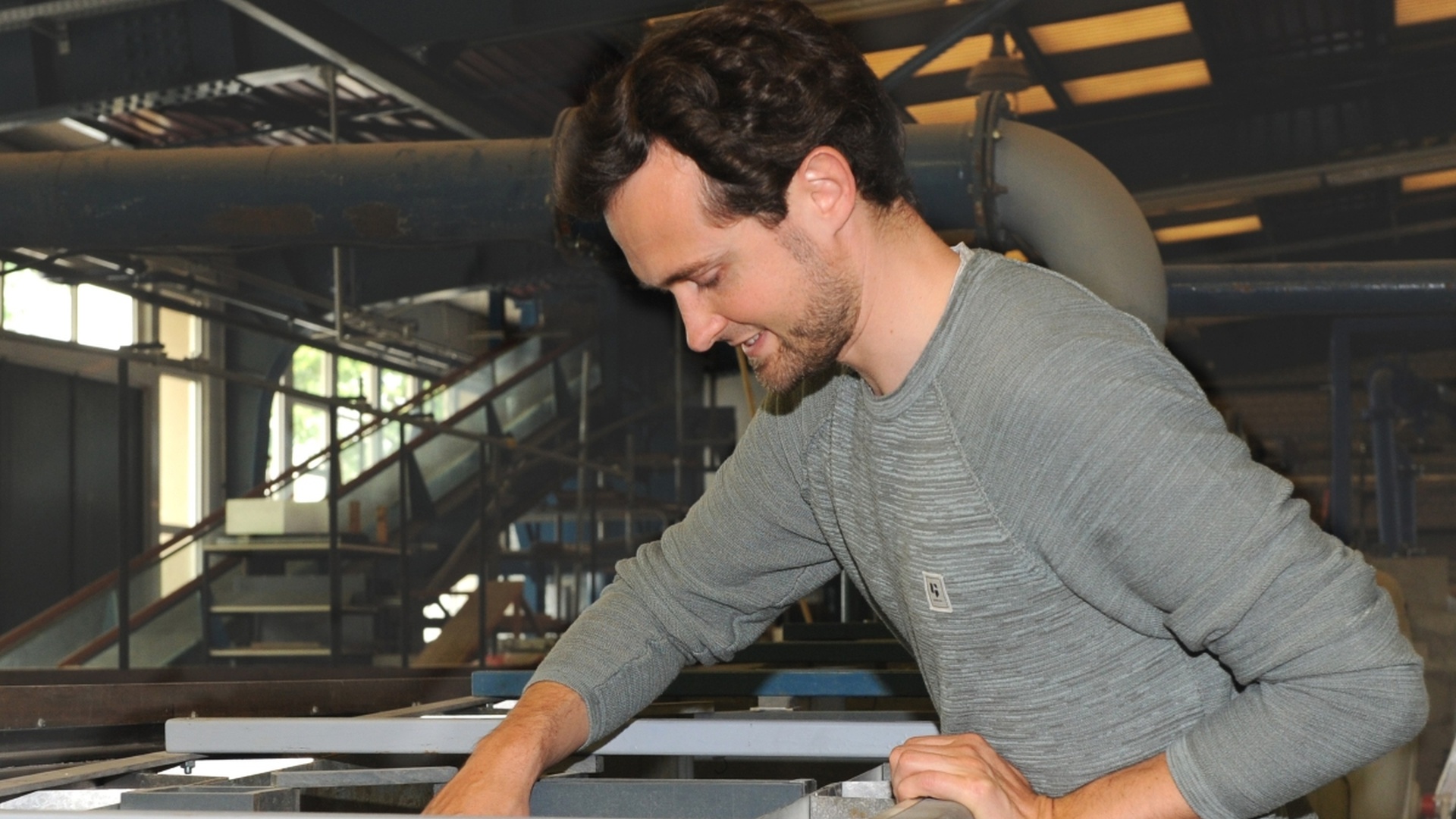 Daniel Beetz arbeitet in einer Fabrikumgebung an einer Maschine.