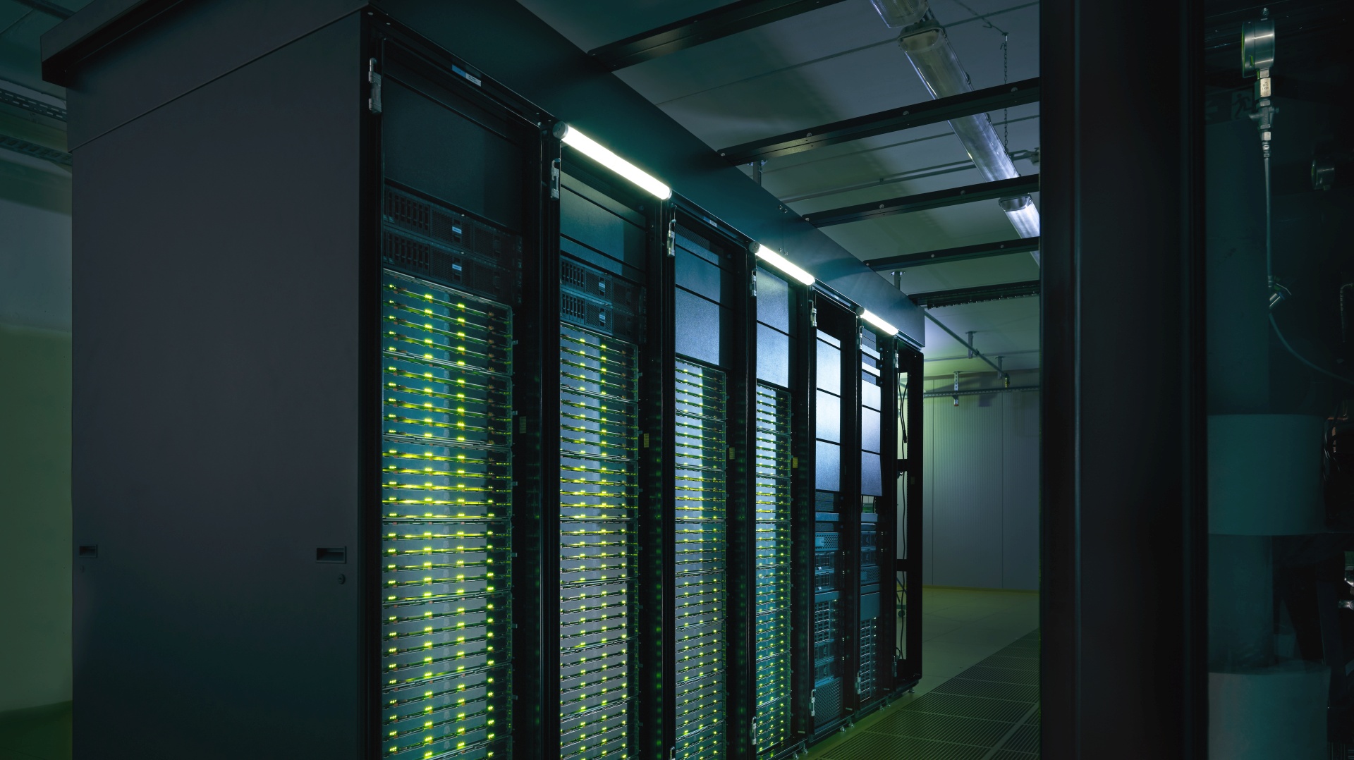 Server racks with glowing green indicator lights in a data center corridor.