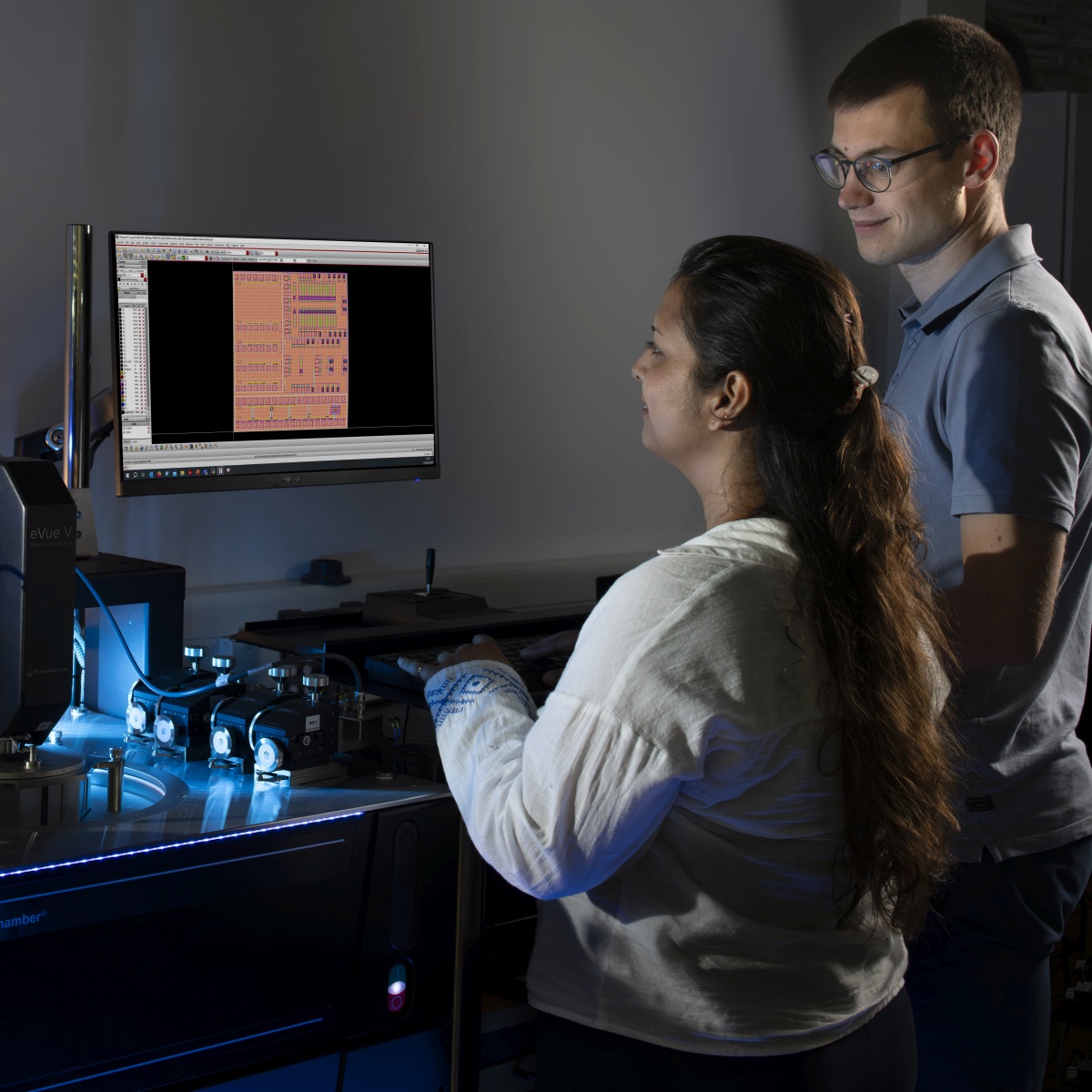 Zwei Personen betrachten technische Diagramme auf einem Computerbildschirm im Labor.