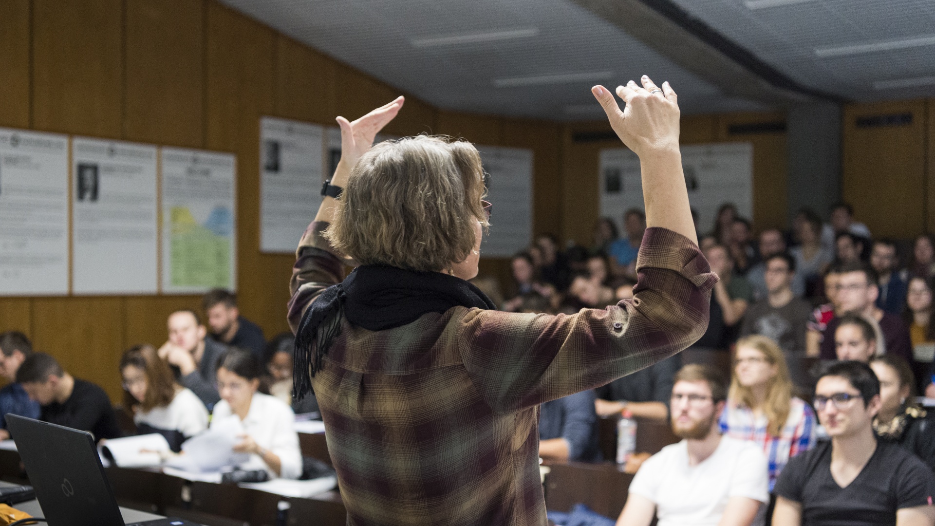 Eine Frau steht vor Studierenden und erklärt ihnen etwas. 